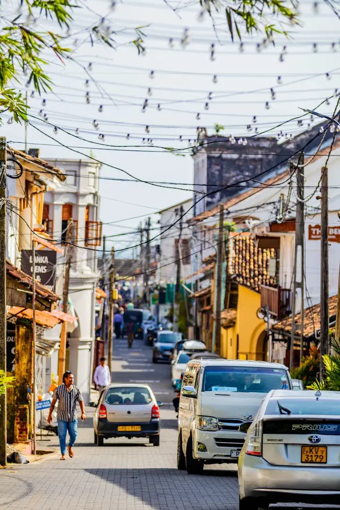 Vibrant urban street view in Galle, Sri Lanka with vehicles and pedestrians under string lights.